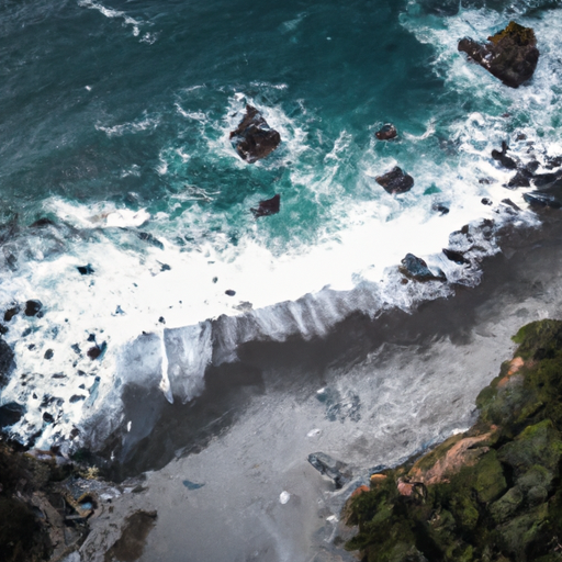 צילום אווירי של חוף מבודד בחוף האוקיינוס השקט, גלים מתנפצים על החופים הסלעיים